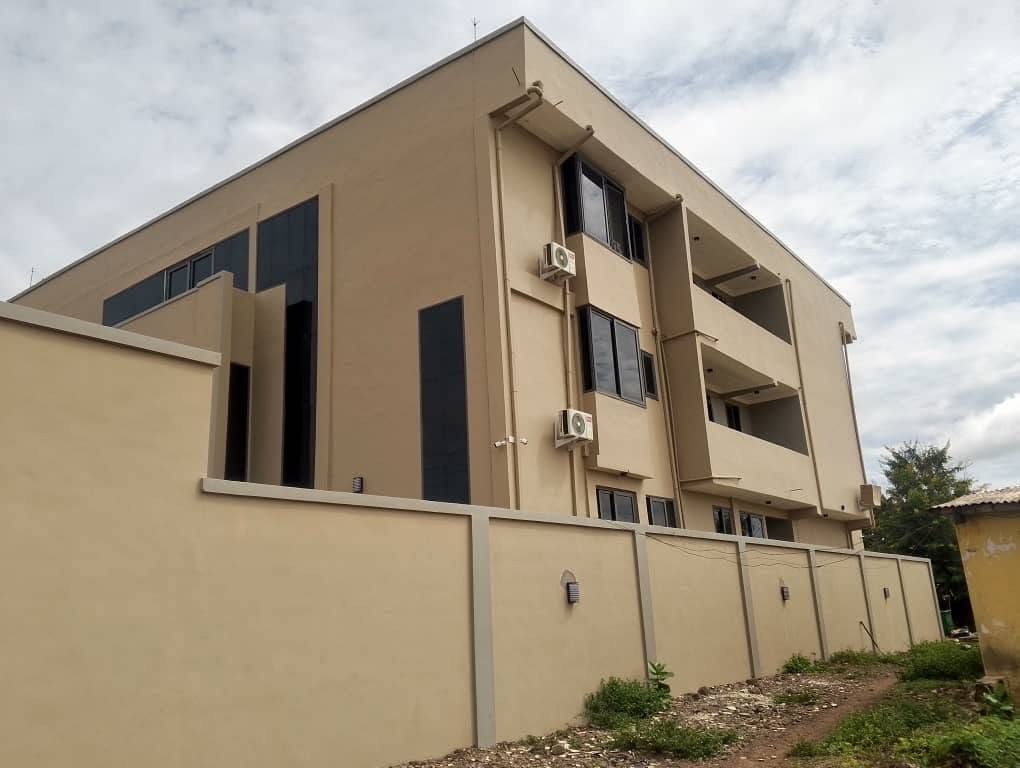 Completed X-Mell apartment building with balconies and perimeter wall — turnkey residential construction in Ghana