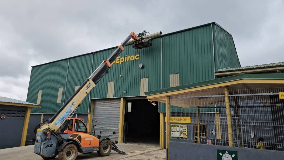 X-Mell telehandler lifting a large pipe section onto an industrial workshop building during installation works