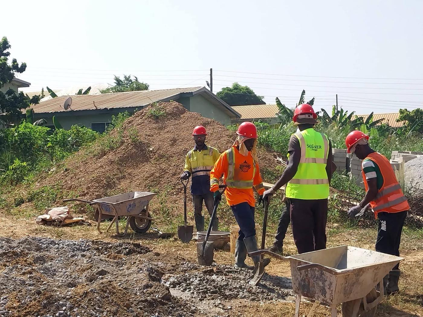 X-Mell crew in red safety helmets and high-visibility vests mixing concrete on a residential site